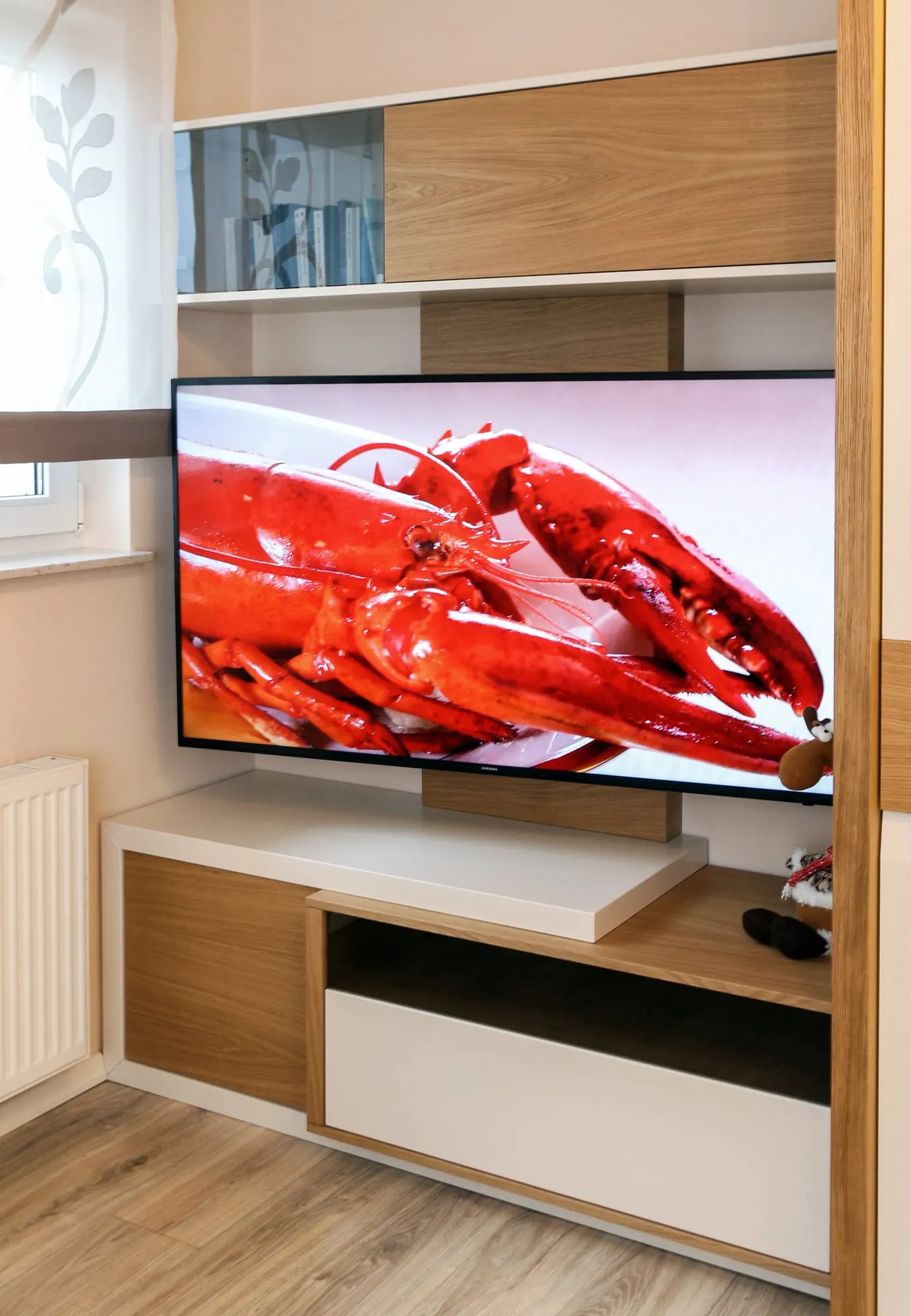 Zabudowa pod telewizor z otwartą półką i szufladą w bieli z dębowym pasem.