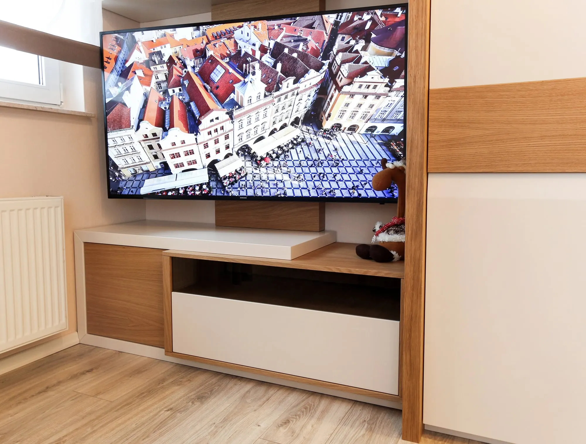 Wnęka na telewizor z otwartą półką i szufladą, obok szafa przesuwna w bieli.