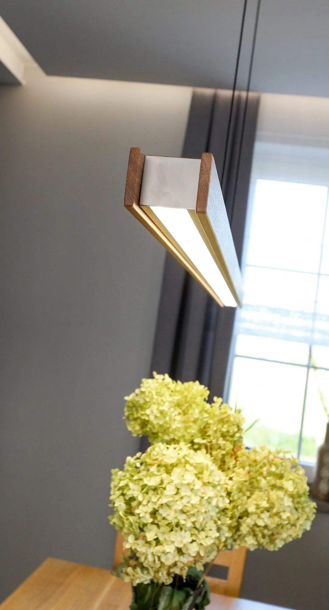 Podłużna lampa wisząca przy oknie w części jadalnej.