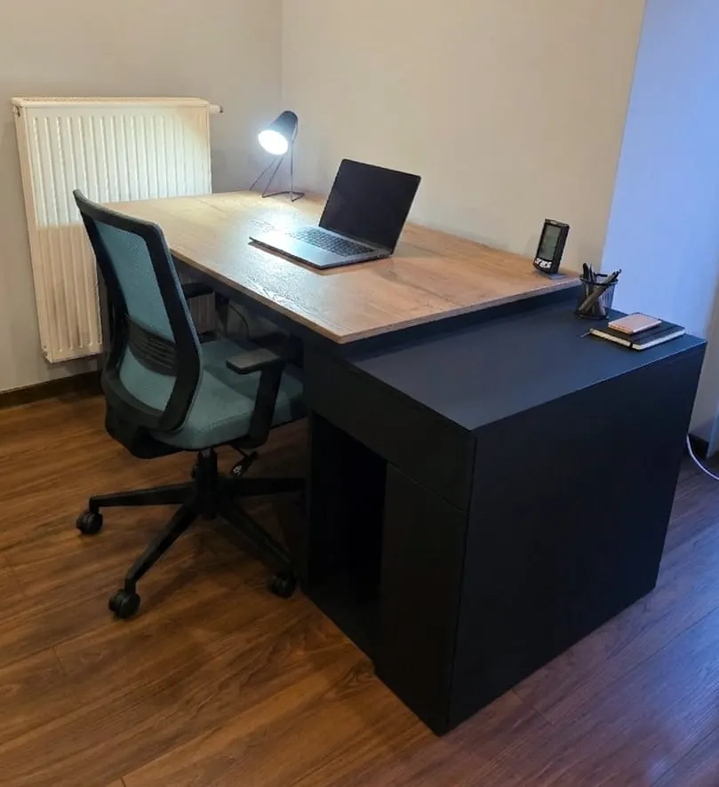 Czarne biurko z drewnianym blatem, lampka i laptop na blacie.