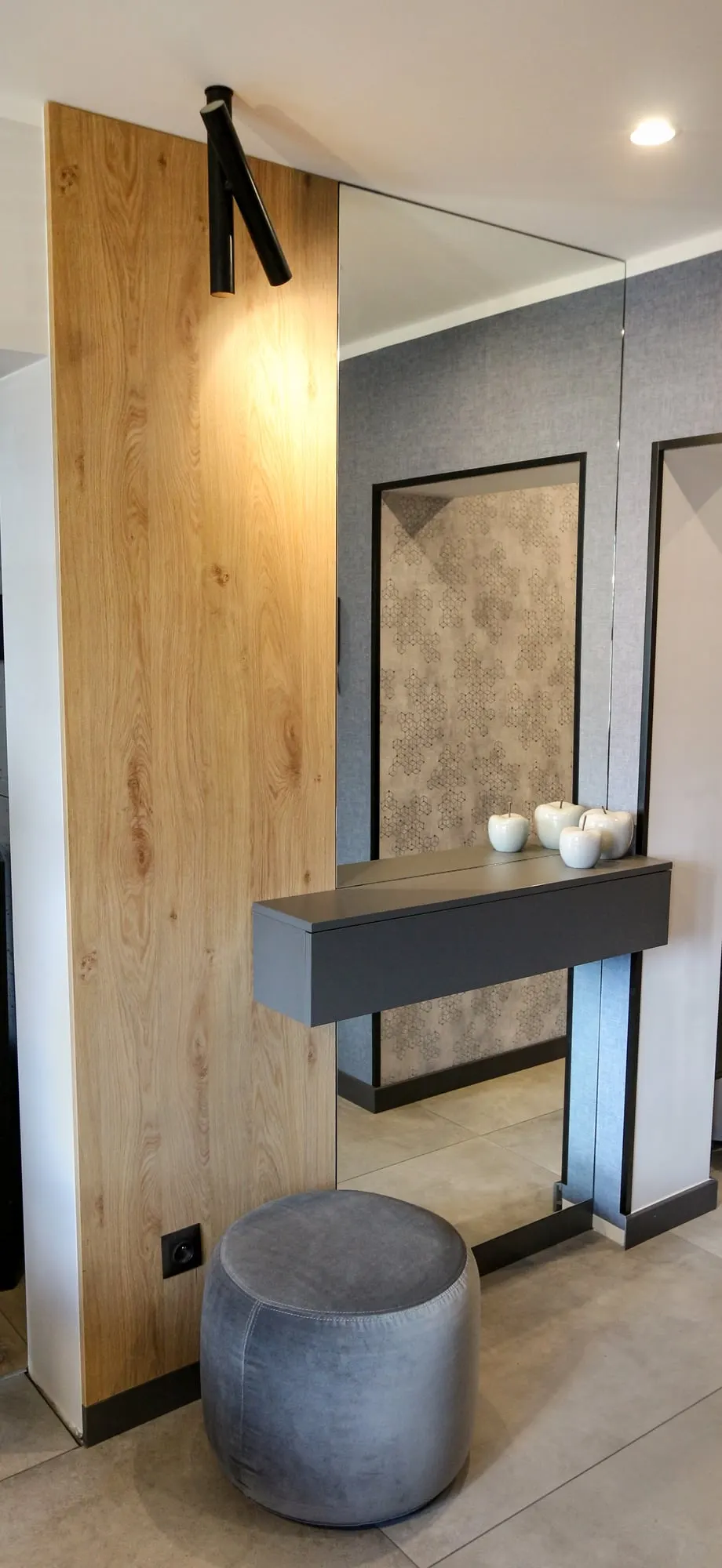 Dębowy panel z lustrem, grafitową półką i okrągłym pufem w narożniku.