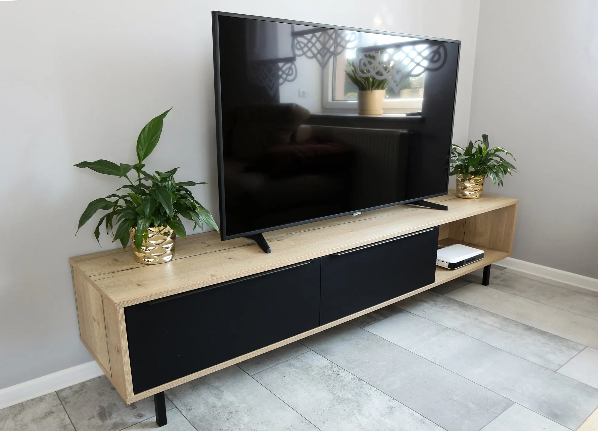 Szafka RTV z dębowym blatem i otwartą wnęką, z telewizorem i roślinami na blacie.